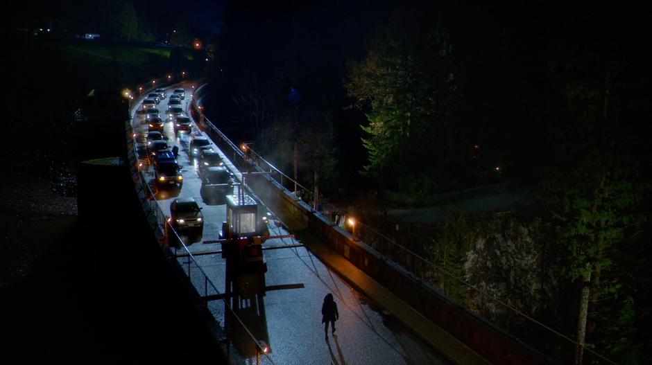 Hartley Rathaway walks up to stopped traffic on the top of a dam.