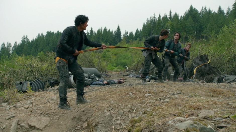 Bellamy is lowered down by Murphy, Finn, and Monroe on their new rope.