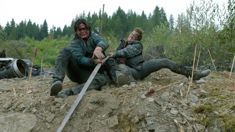 Finn, Murphy, and Monroe struggle to lift Bellamy and Mel up the cliff face.