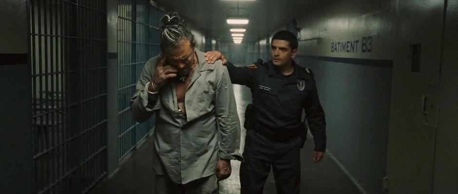 Vanko is escorted down the jail hallway by a guard.