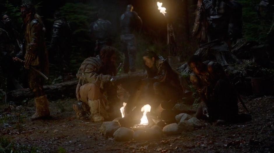 Indra sits by a fire in camp.