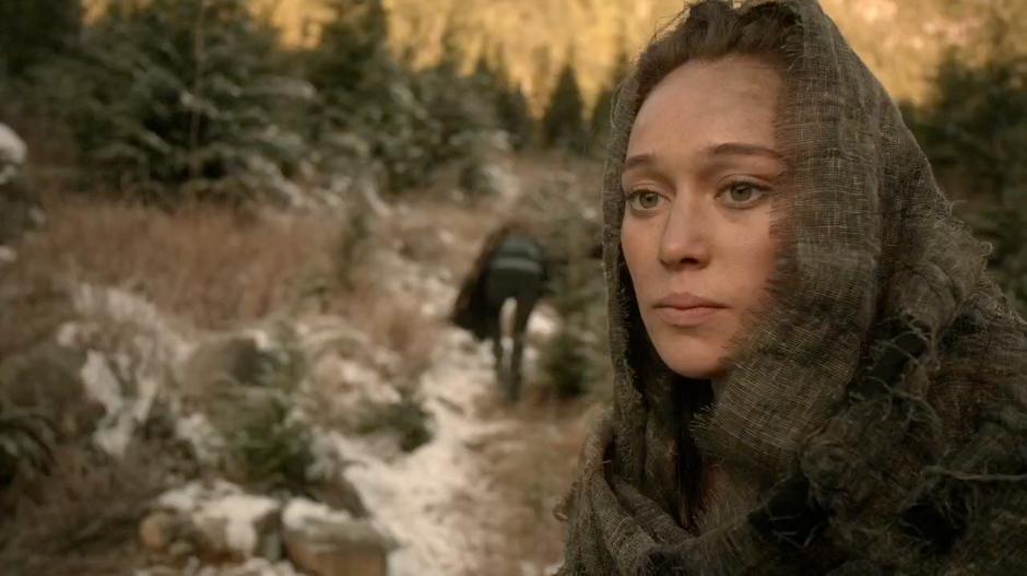 Lexa looks back at the burning ruins of Tondc while Clarke heads up the hill after the sniper.