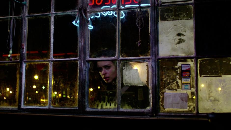 Jessica peers into the bar through the window.