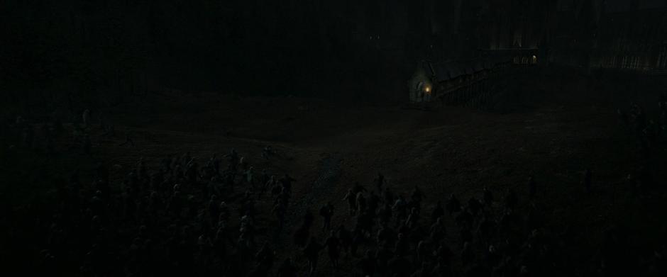 A huge group of Death Eaters run down the hillside towards the entrance to the bridge where Neville is standing.