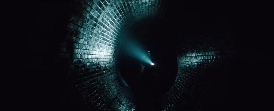 Members of the Ghost Protocol team walking through a dark, brick-lined tunnel.