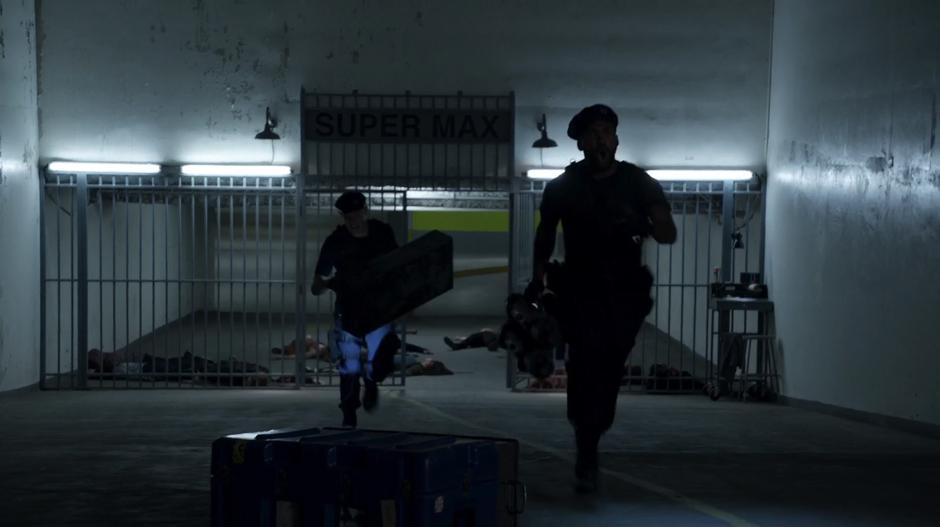 Two of the paramilitary soldiers run out of the parking garage entrance.