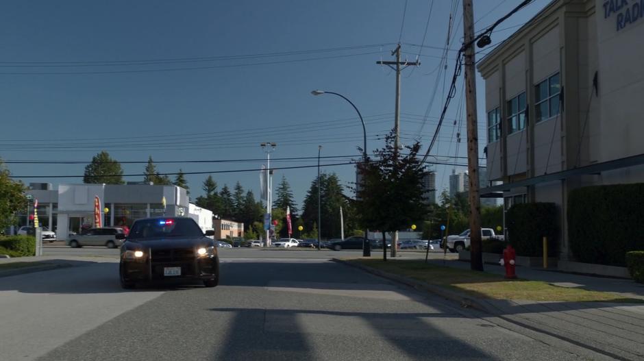 Clive's police cruiser turns off the main road towards the radio station.