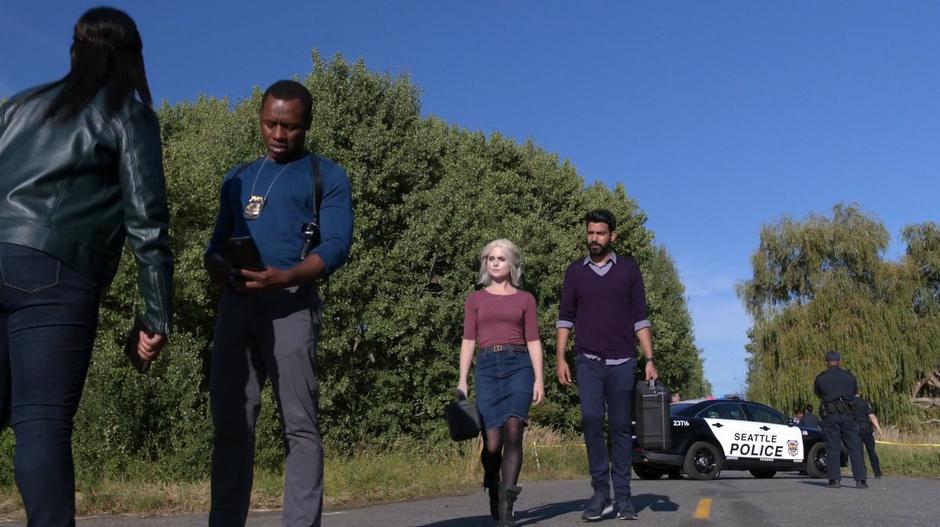 Ravi and Liv walk down the street to the scene of the crash.