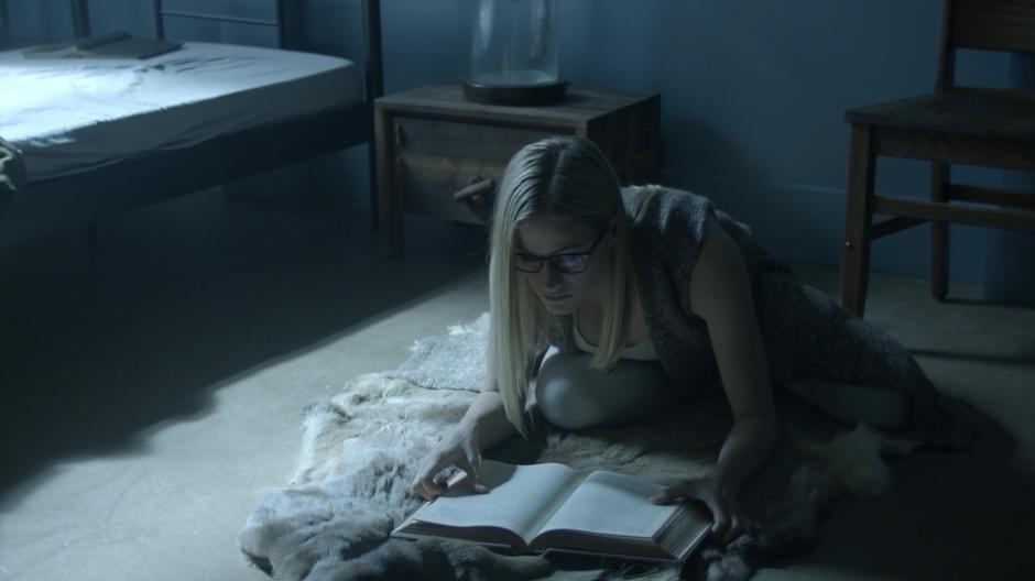 Alice looks up from her book which she is studying on the floor of her room.