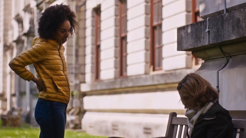 Bill stands over Heather who is sitting on a bench and asks what is wrong.