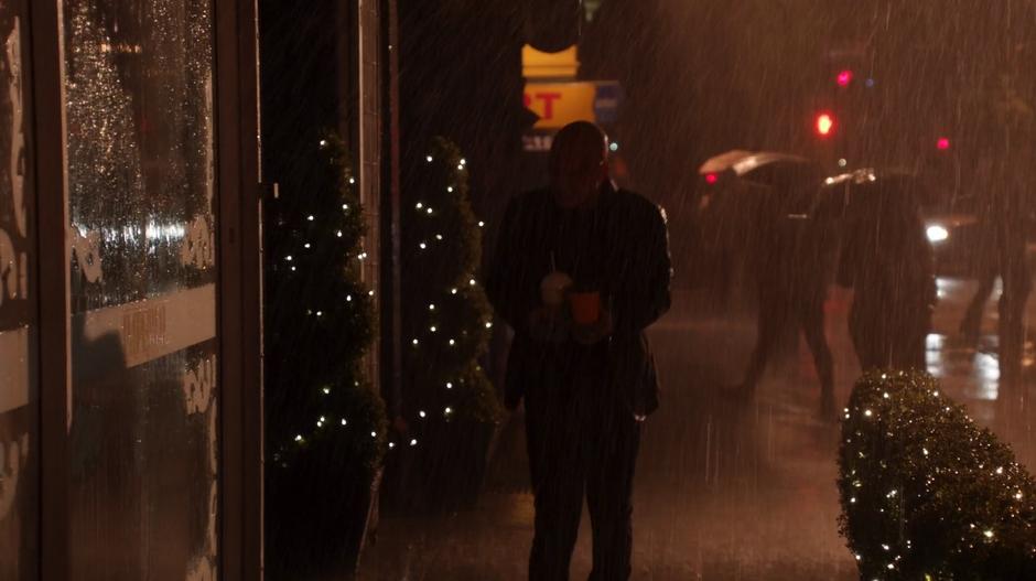 Don E. walks down the raining street past the club holding coffee for his new boss.