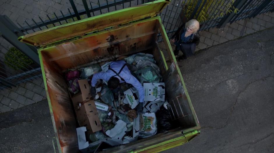 Liv stands by while Clive searches through the dumpster for the bag.