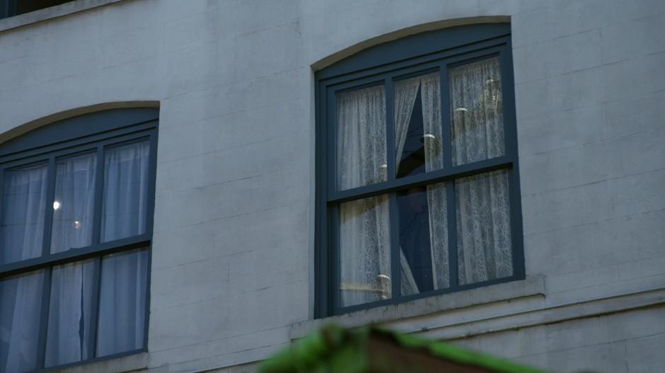 Clive looks through the curtains of the apartment.