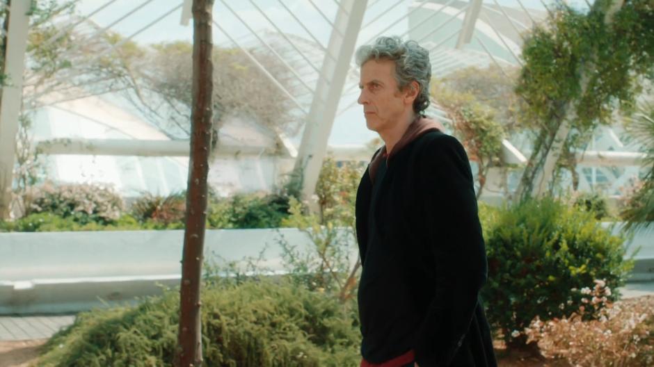 The Doctor looks around quizzically while walking through one of the greenhouses.