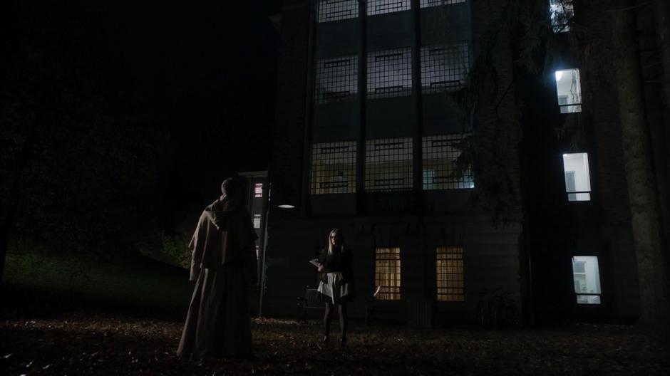 Friar Joseph appears in front of Alice as she is walking in front of the building after class.