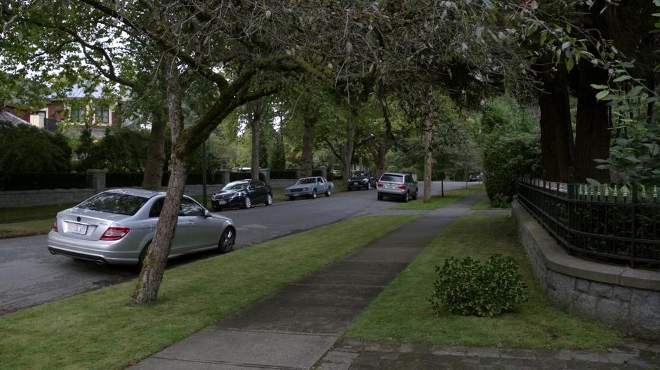 Ravi and Major sit in their car just down the street from the mansion.