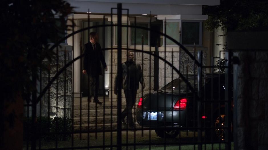 Osborne Oates and his bodyguard walk out of the front door to his car.