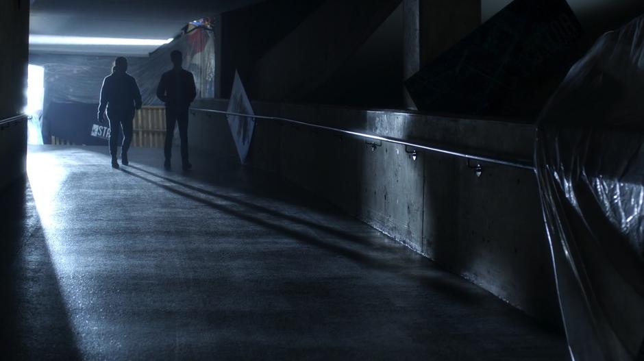 Cisco walks down the lobby ramp with Barry past various tarps covering up the long abandoned building.