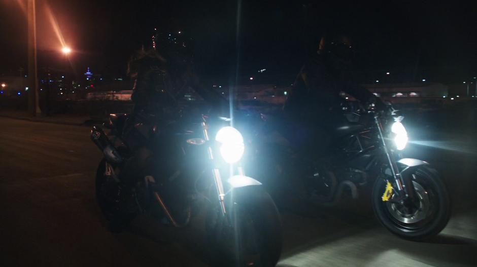 Dinah and Oliver continue driving their motorcycles towards the conflict.