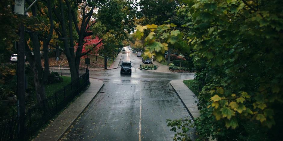 The Commander's car drives down a wet street out front of the house.