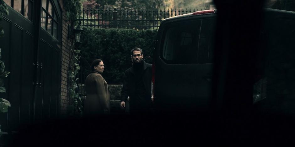 An Eye walks around the side of his van in the driveway while Aunt Lydia stands nearby.