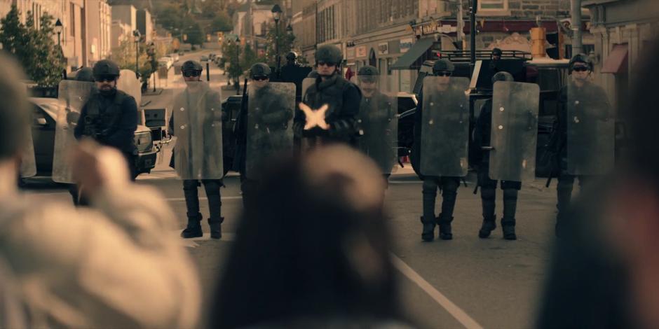 One of the officers with a machine gun opens fire on the crowd while the whole line advances.