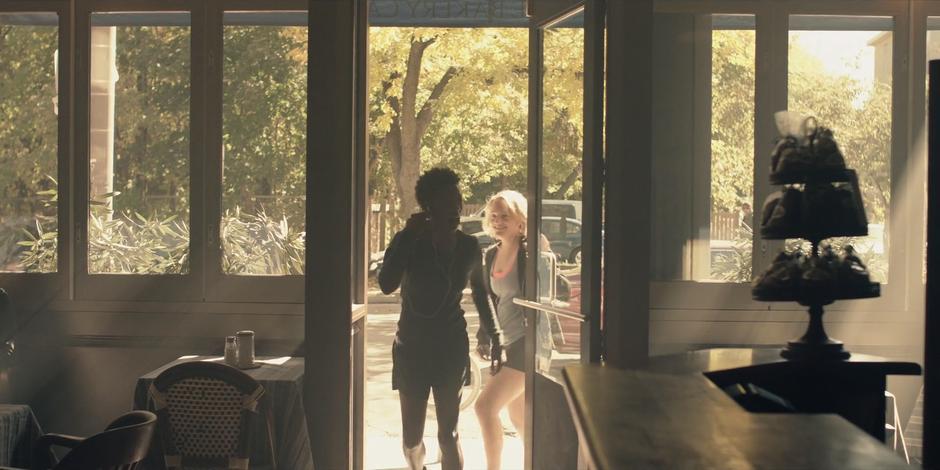 Moira and June enter the front door of the cafe.