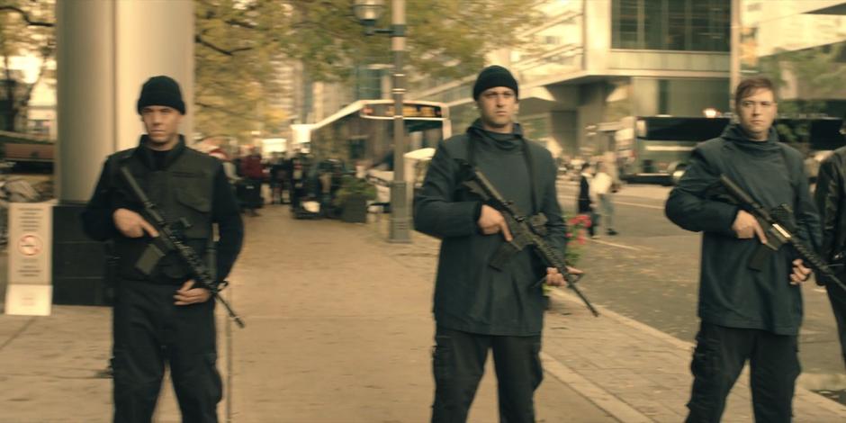 Several guards with large guns stand by as the woman are escorted from the building.