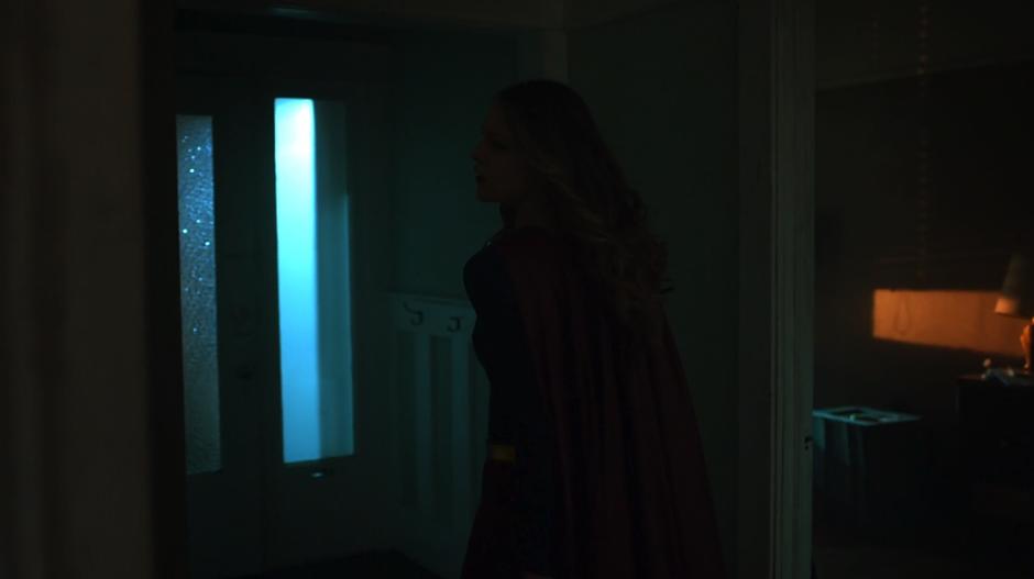 Kara searches around the interior of the house while calling Alex's name.