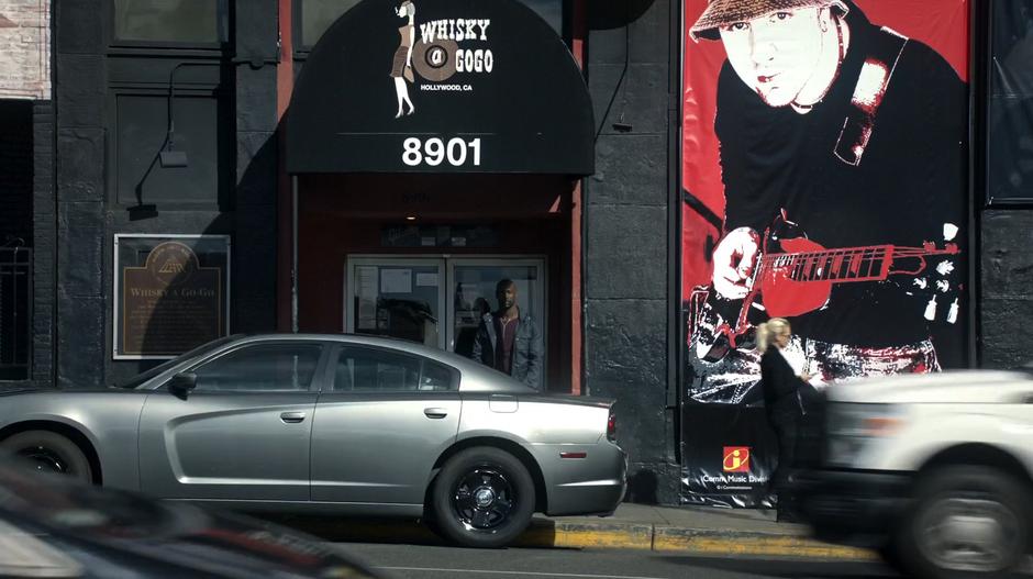 Amenadiel stands in the doorway to the club across the street from the crime scene.