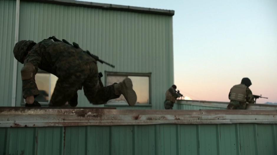 Major leaps over the railing onto the rooftop where the bad guys are firing down on his coworkers.