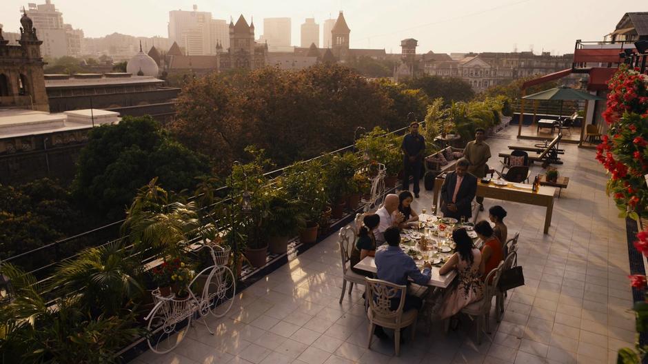 Kala and Rajan's family joins them for a family dinner on the balcony of their new home.