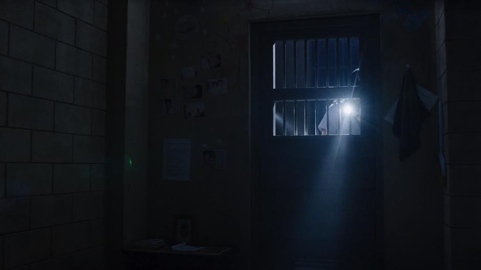 A guard shines his flashlight into the cell while calling for Sun.