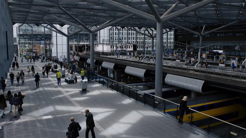 Riley stands on the upper level of the station looking down and waiting for Will's train to arrive.