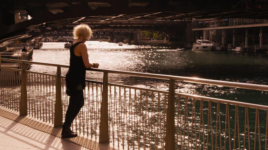 Riley leans against the railing at the edge of the park while the sun reflects beautifully off the water.