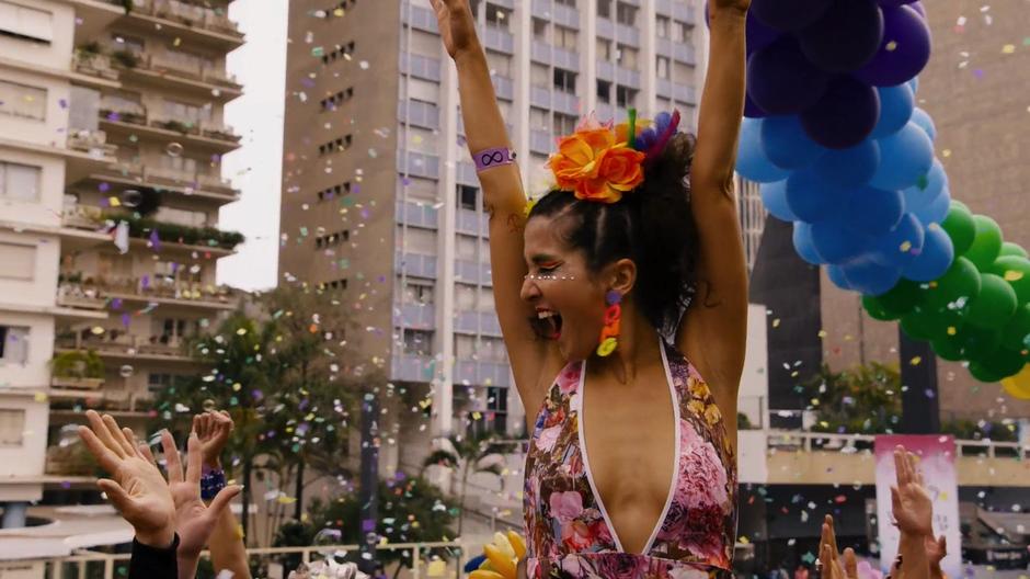 Dani throws her arms up into the air in celebration while surrounded by confetti and bubbles.