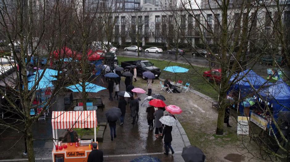 People walk around the market in the rain with umbrellas.