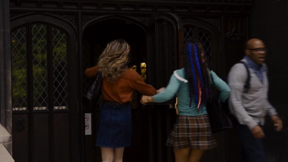 Nomi and Amanita rush in through the door into the lecture hall.