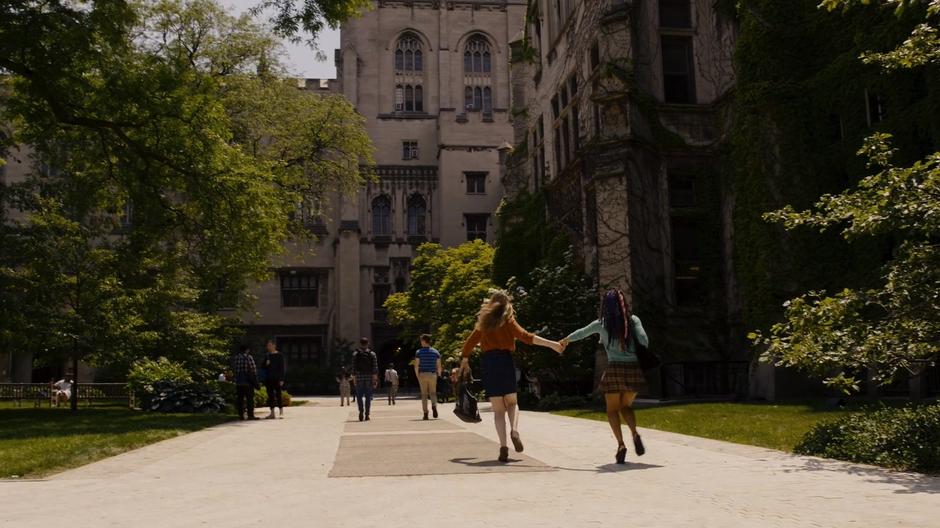 Nomi and Amanita run hand-in-hand through the quad.