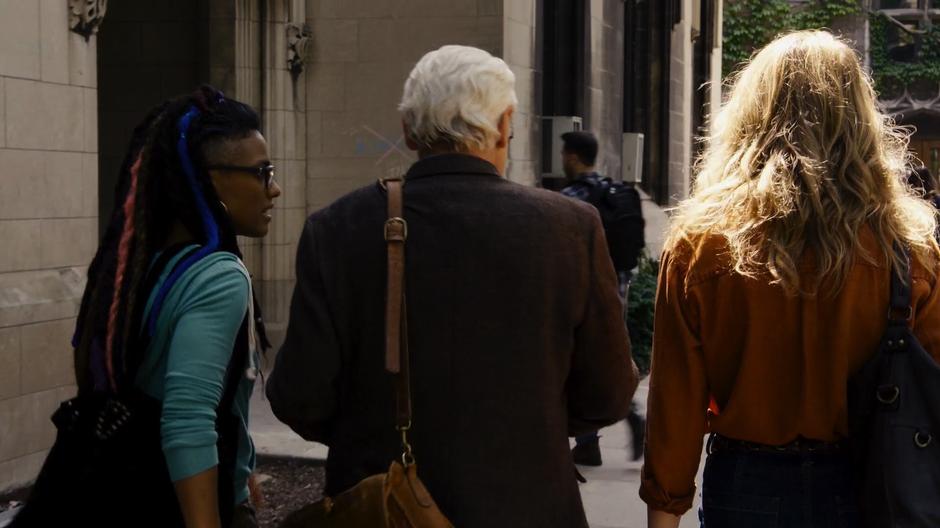 Amanita asks a question of Professor Kolovi while walking with him and Nomi to the office.