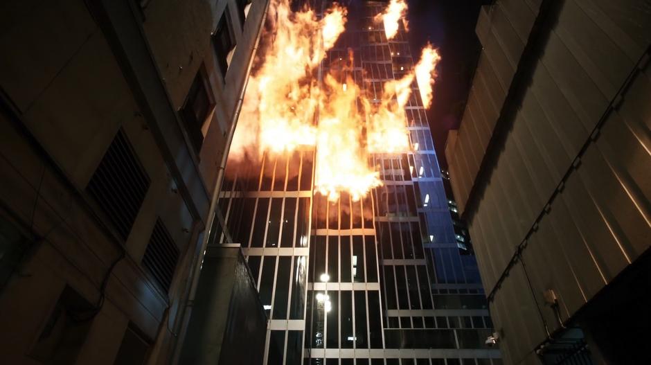 Several floors of the skyscraper burn at the end of the alley.