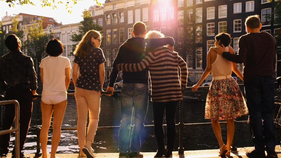 Will and Riley stand by the canal with their arms around one another while the rest of the cluster gathers around.