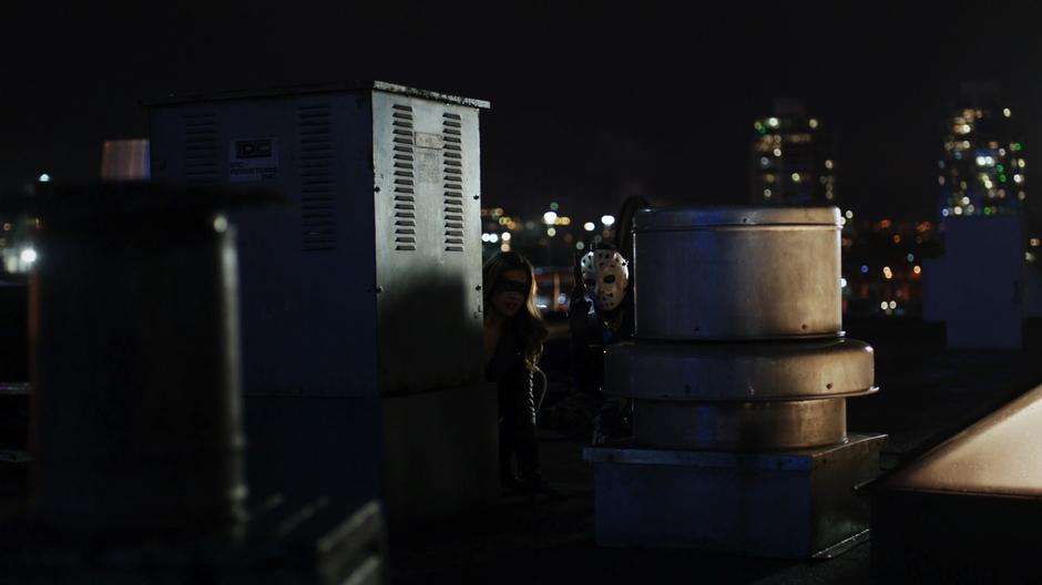 Dinah and Rene hide behind some air handling equipment watching the bad guys.