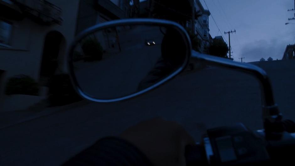 Bendix's car is visible in Amanita's side mirror as she drives up the hill.