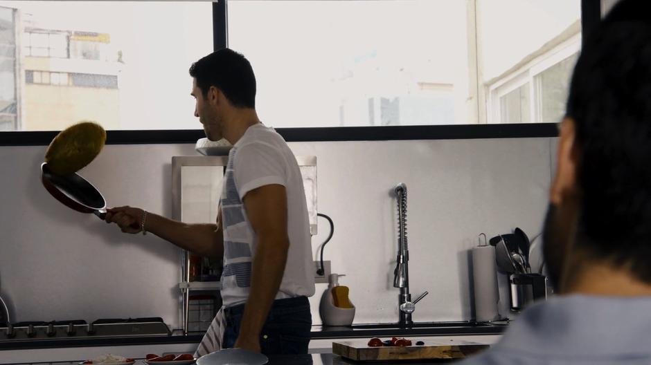 Lito cooks breakfast in the kitchen while Hernando watches.