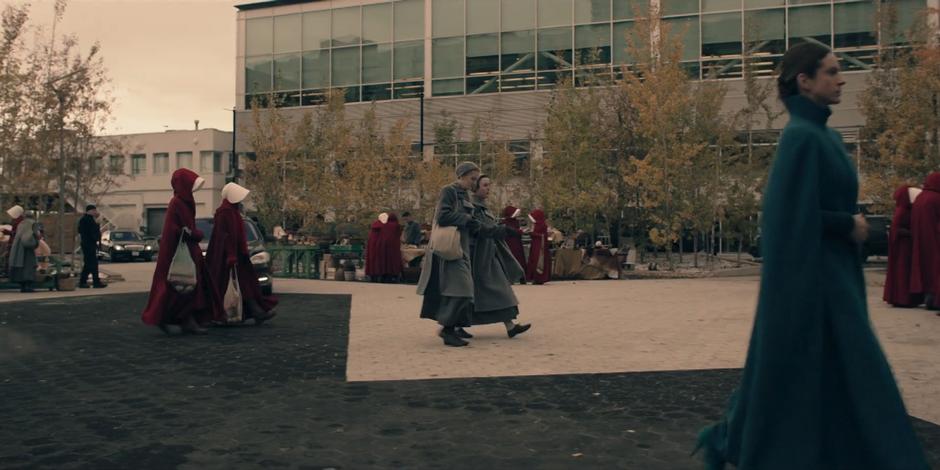 Offred and Ofglen walk across the busy square to the market stalls.