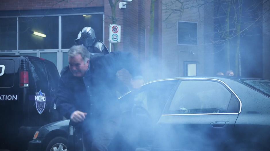 A man runs from his car as a Daxamite soldier points their gun at him.