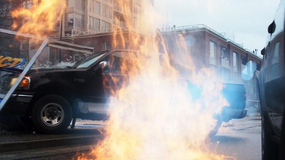 A pickup truck crashes into a bus stop while being surrounded by flames.