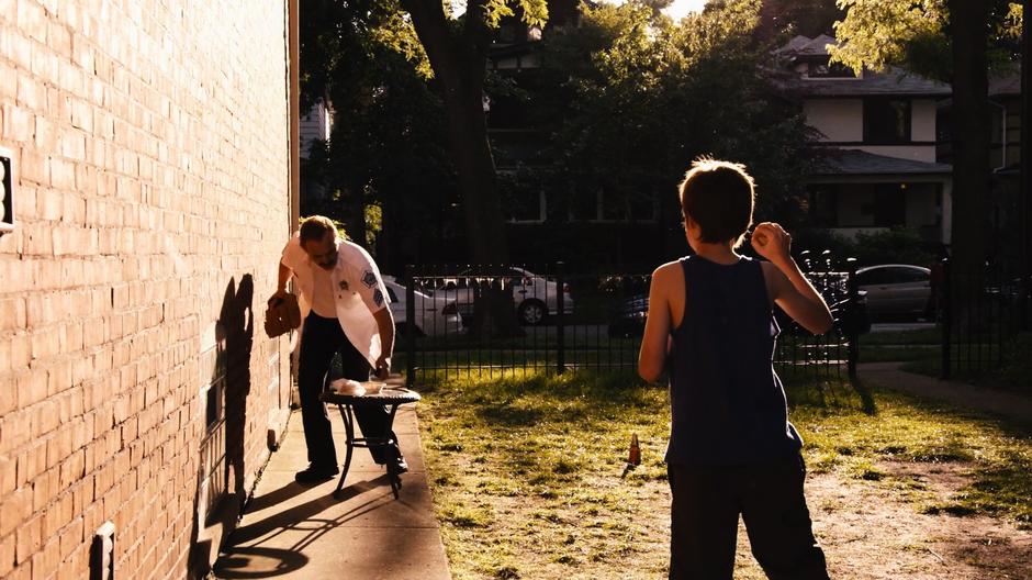 Michael Gorski checks his phone while young Will waits to throw him the ball.