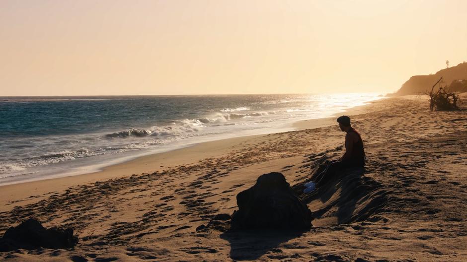 Lito sits alone on the sand looking out over the ocean.